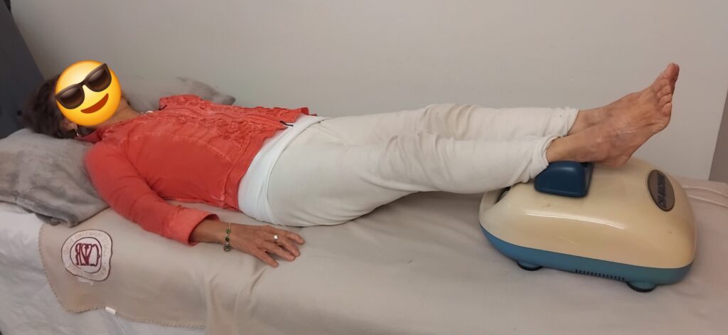 Frau entspannt sich liegend auf einer Liege, während ihre Füße in einer Chi-Maschine sanft bewegt werden.